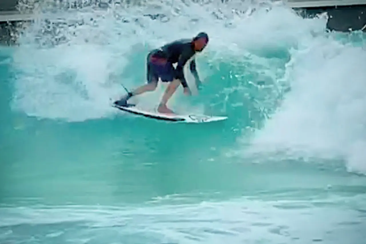 A surfer riding an artificial wave at a wave pool