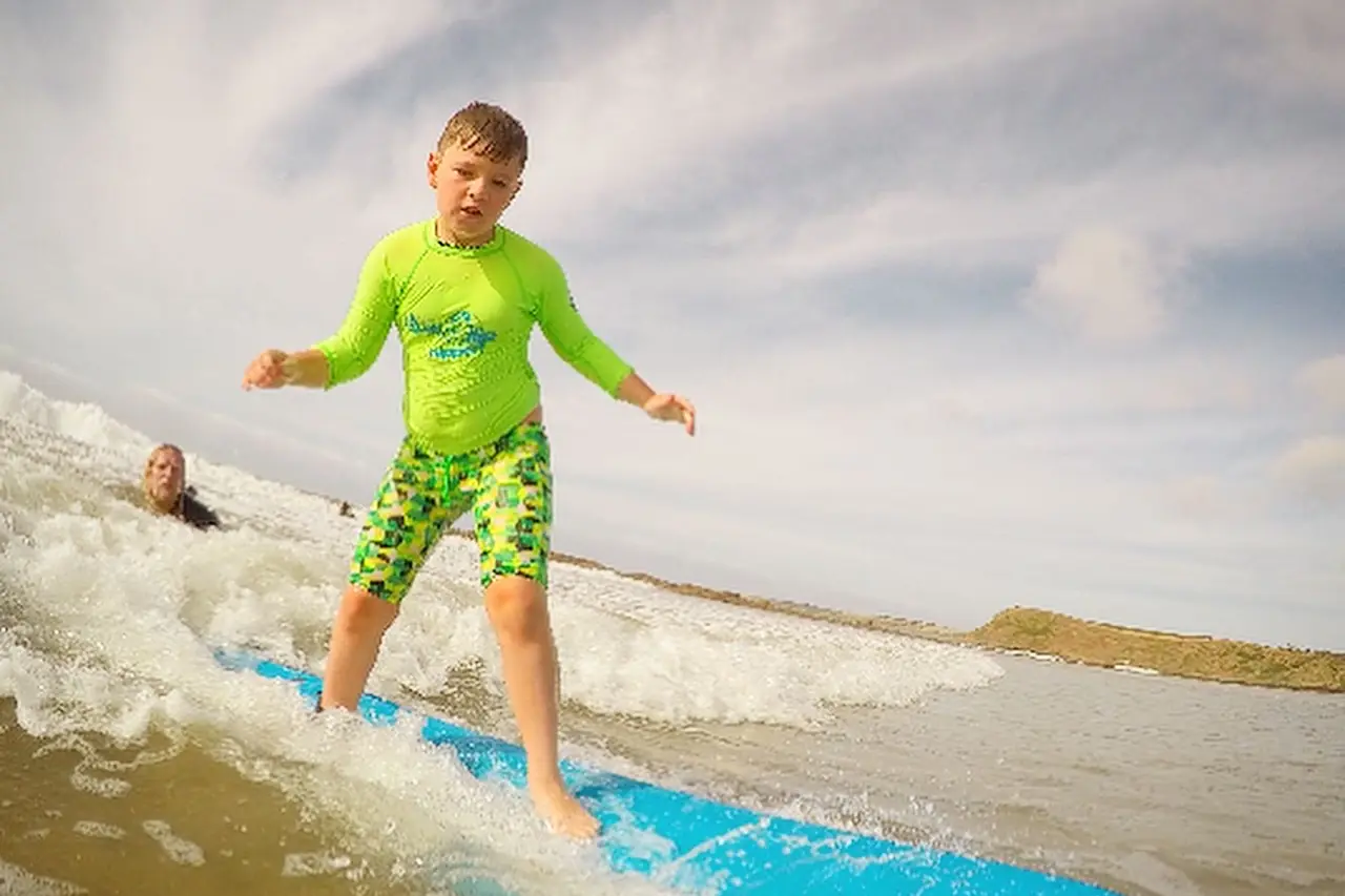 A young student riding a wave on a foam board at Smiths Beach