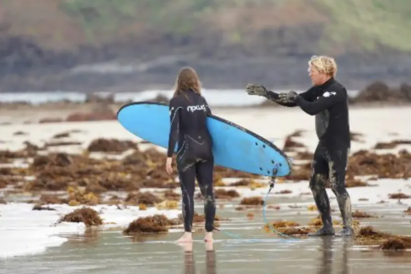 Pro Surf Coaching boards and wetsuits laid out on the sand
