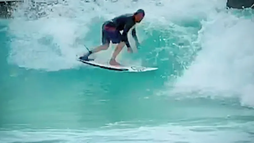 A surfer riding an artificial wave at a wave pool